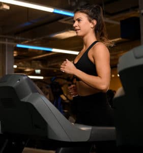 young woman on exercise machine after using the best energy supplements for fatigue