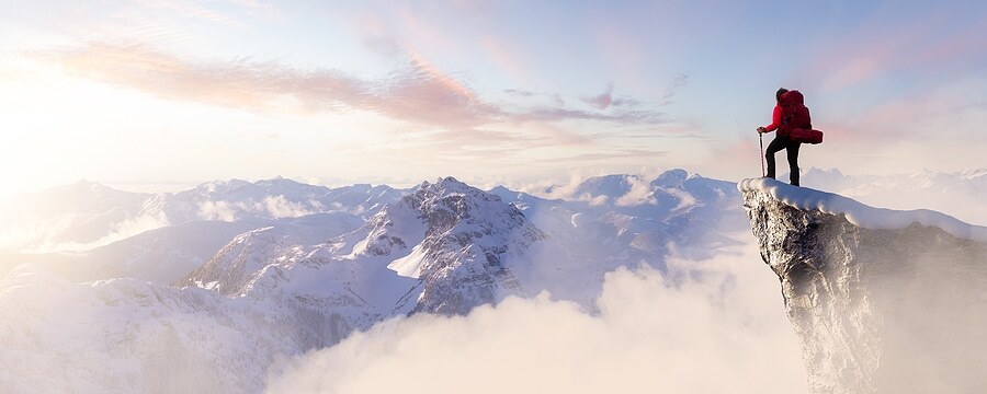 man on mountain top looking over a valley with clouds and wondering about the best supplements for energy
